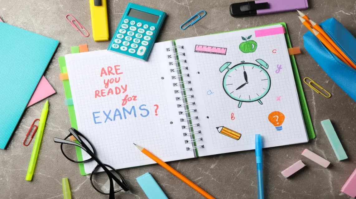 دفتر مفتوح كُتب عليه «Are you ready for exams?» تحيط به أقلام ومسطرة وآلة حاسبة ونظارة.