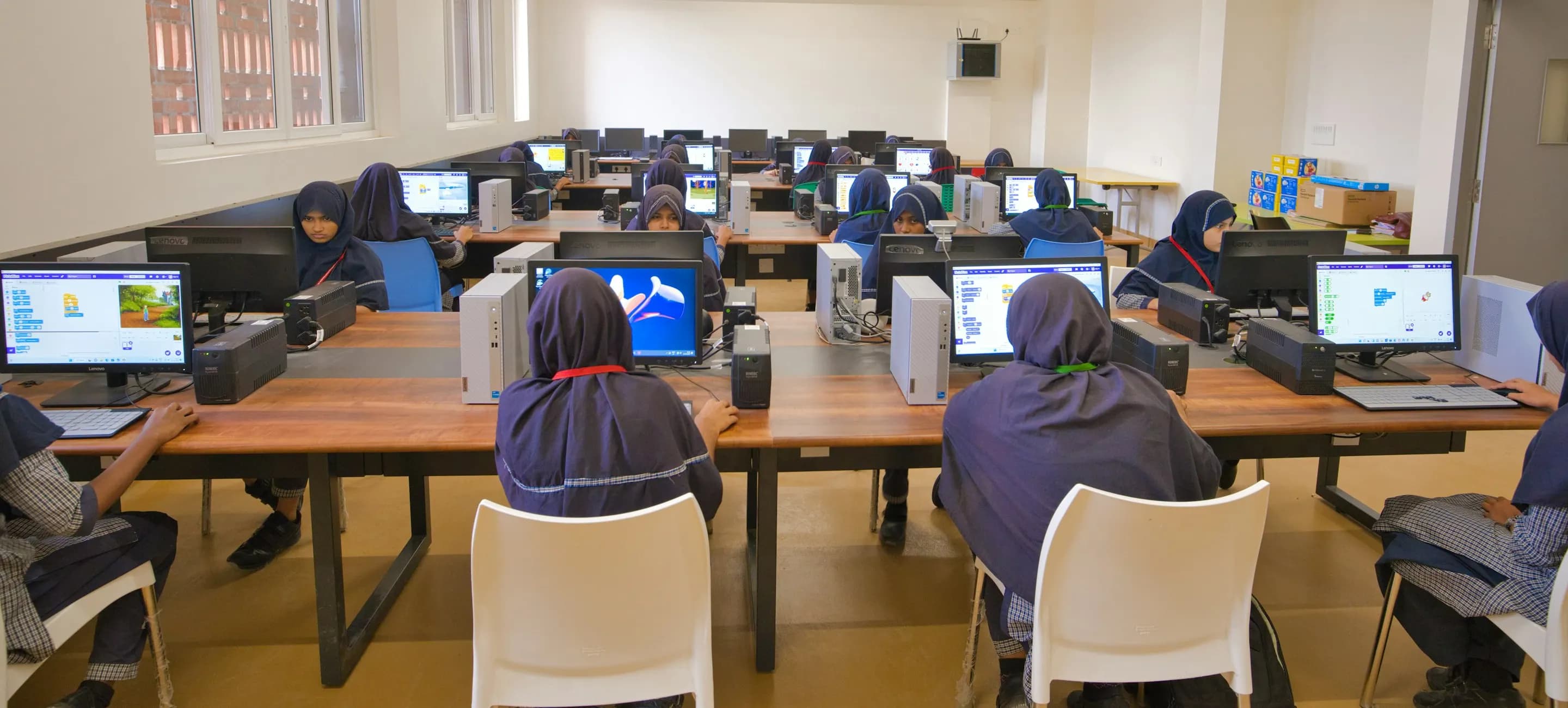 Students working at desktop computers in a school computer lab during a lesson